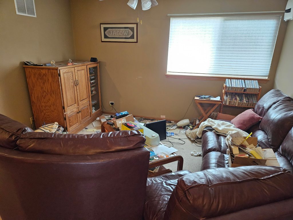 Messy living room with furniture scattered and debris during estate cleanout job by Junk Nurse in Aurora IL