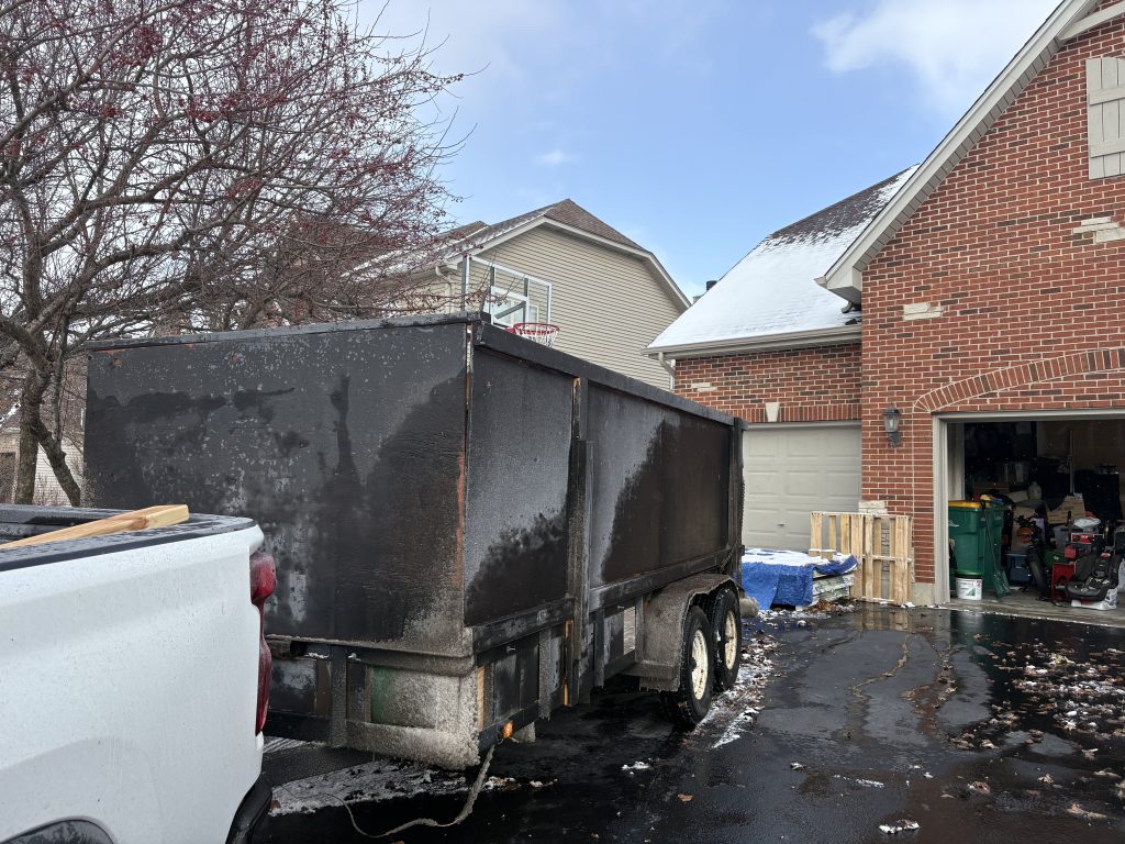 Junk Nurse dump trailer parked at a suburban home driveway during a winter cleanout job in Aurora IL area