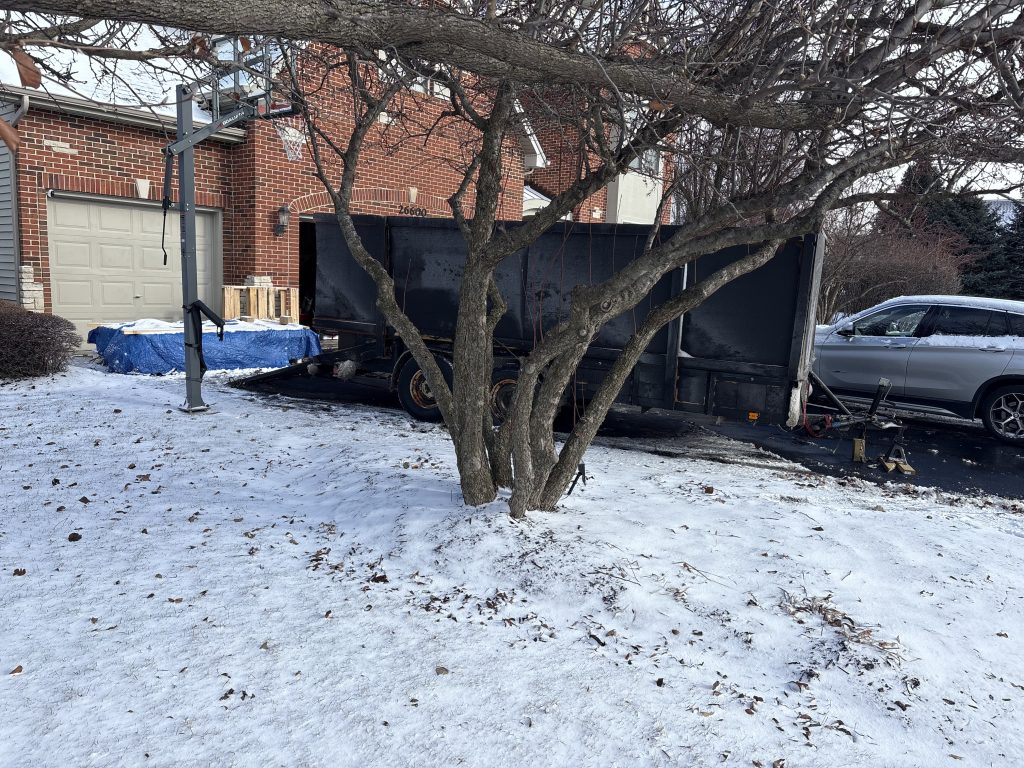 Junk Nurse dump trailer staged in residential driveway during a snowy winter day job near Batavia IL