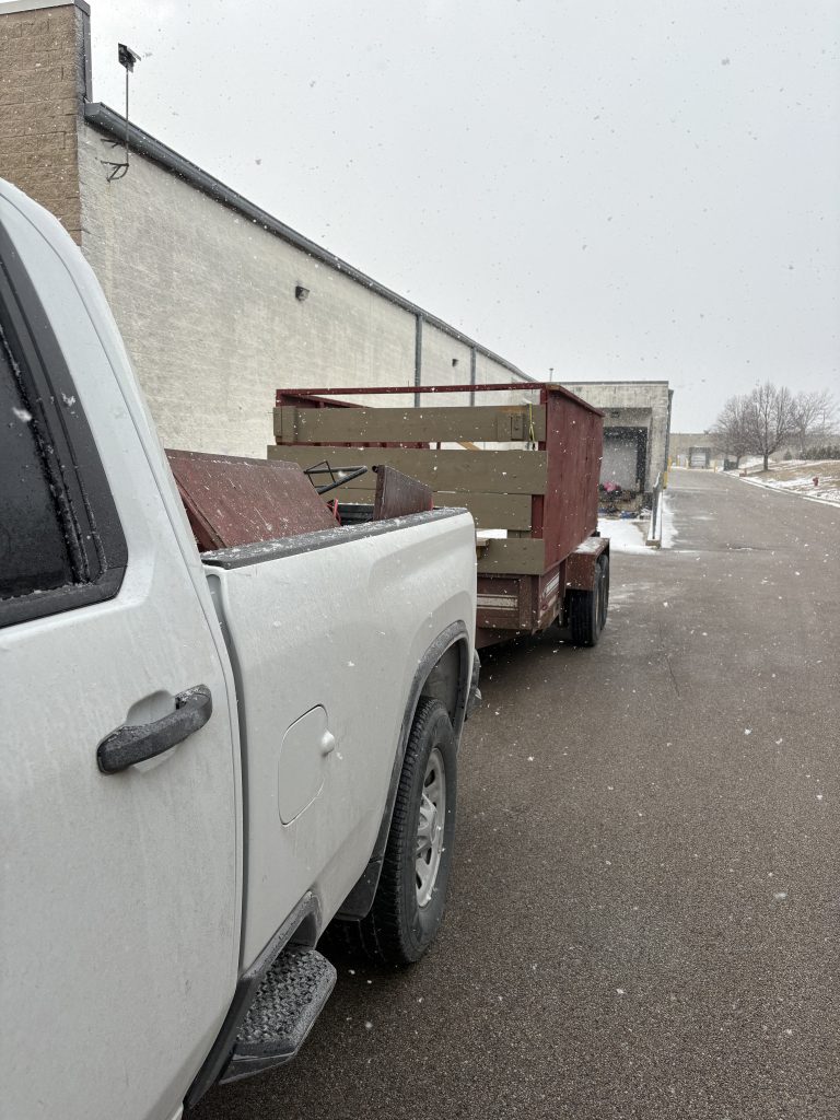 Junk Nurse white truck with red trailer in a snow-covered parking lot during a winter junk removal job near Montgomery IL