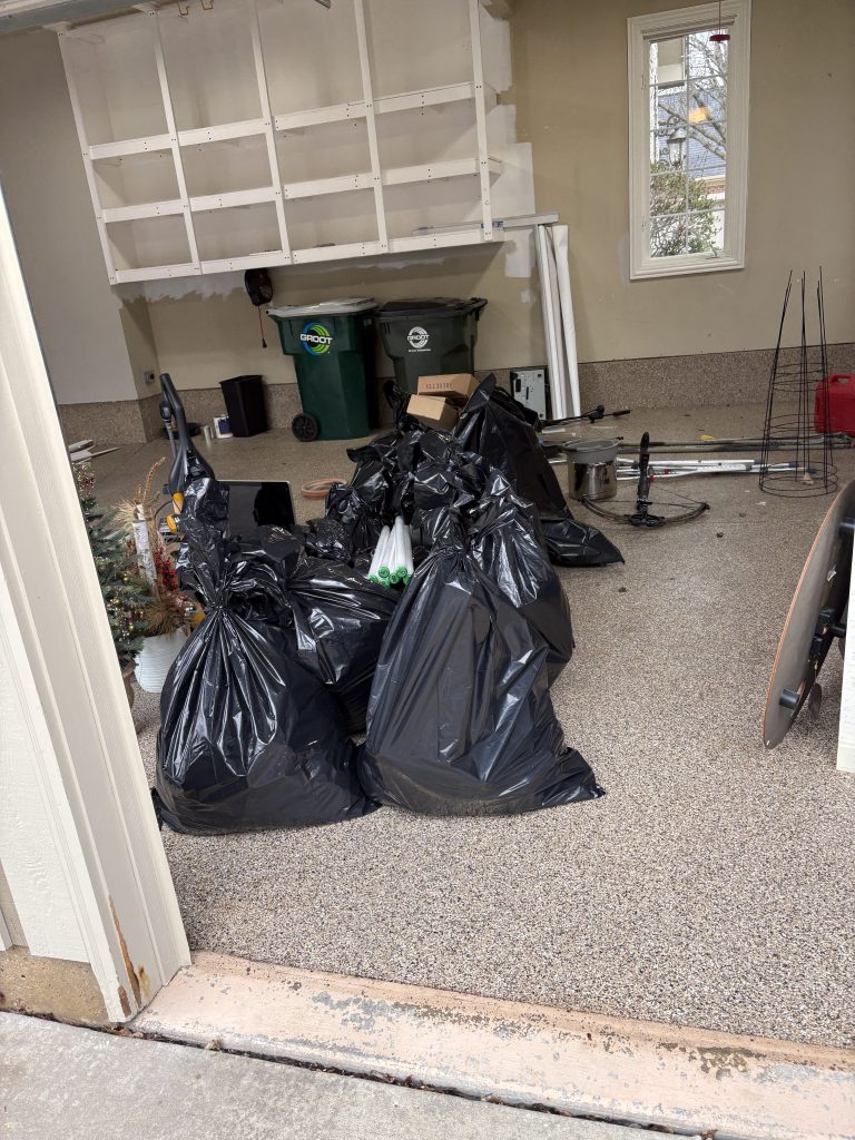 Garage packed with trash bags and debris staged for removal during a Junk Nurse garage cleanout in Aurora IL