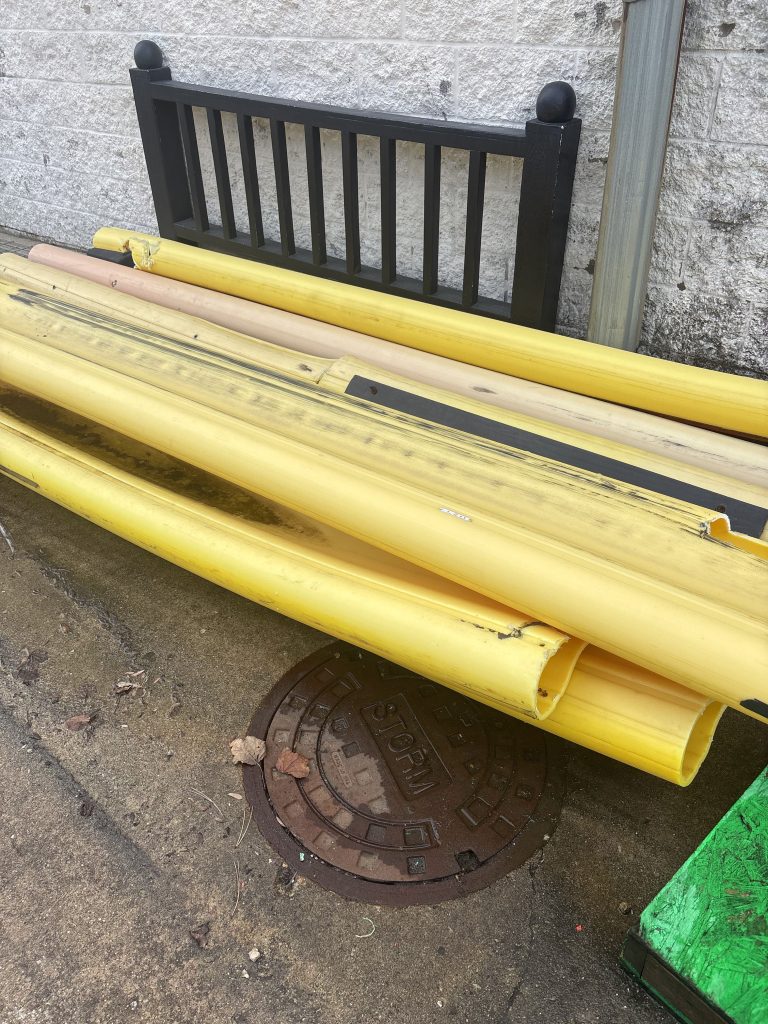 Yellow pipes and tubing staged outside for removal as part of a Junk Nurse commercial cleanout service