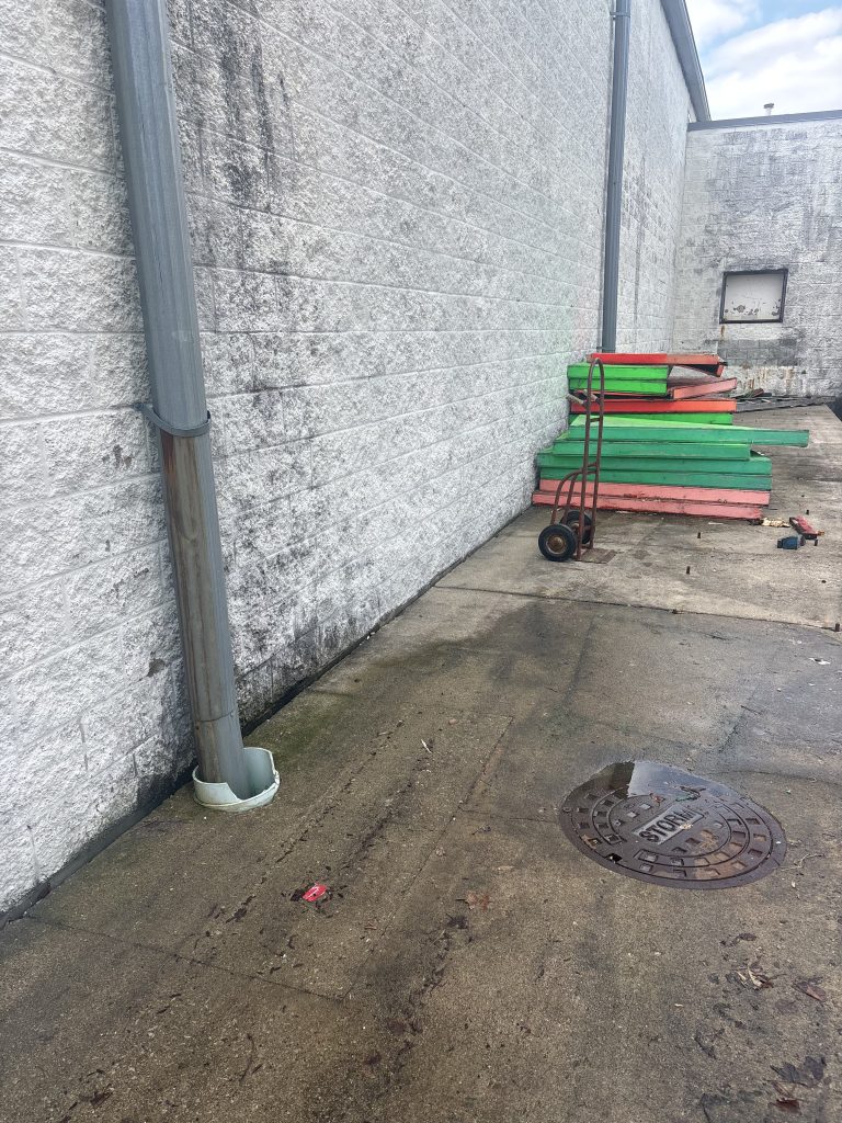 Green and red pipes staged against commercial building wall for removal by Junk Nurse in Aurora IL