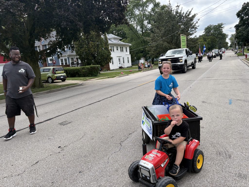 Kids riding Junk Nurse branded toy tractor through Aurora IL neighborhood