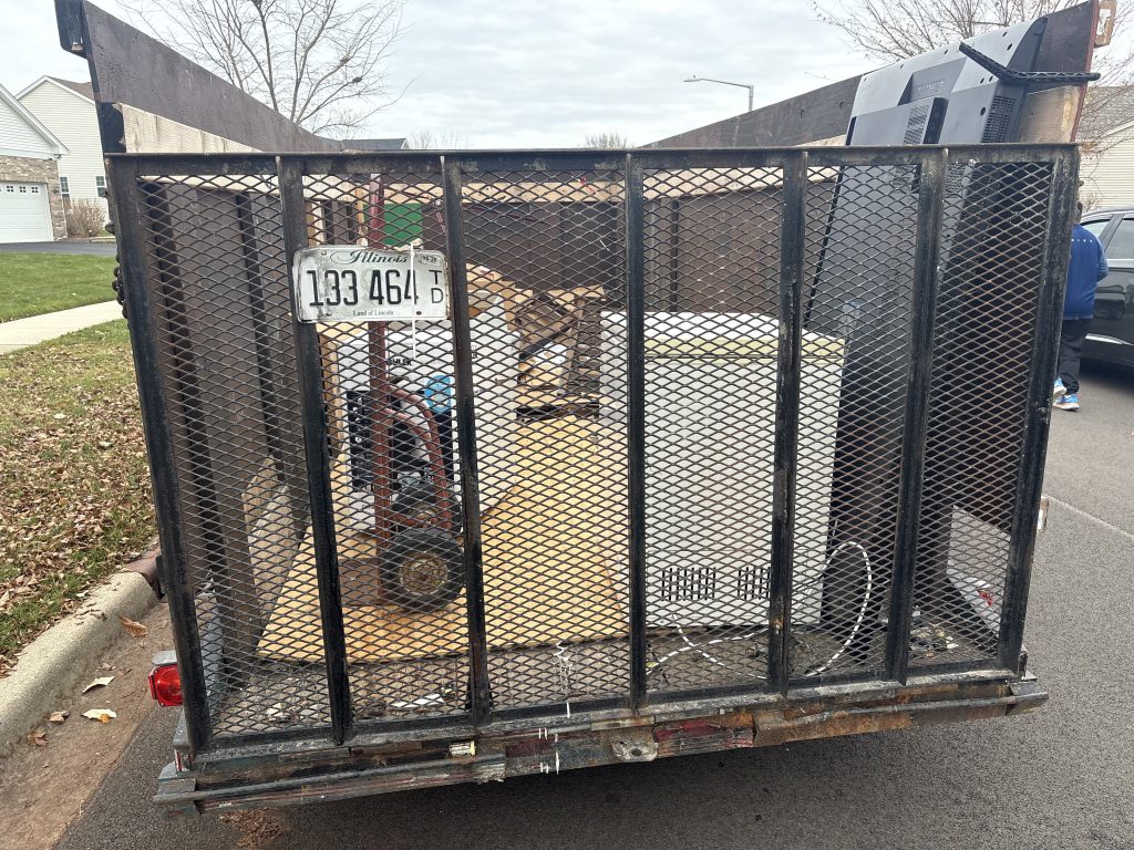 Junk Nurse open mesh trailer fully loaded with junk and debris after a cleanout job in Aurora IL